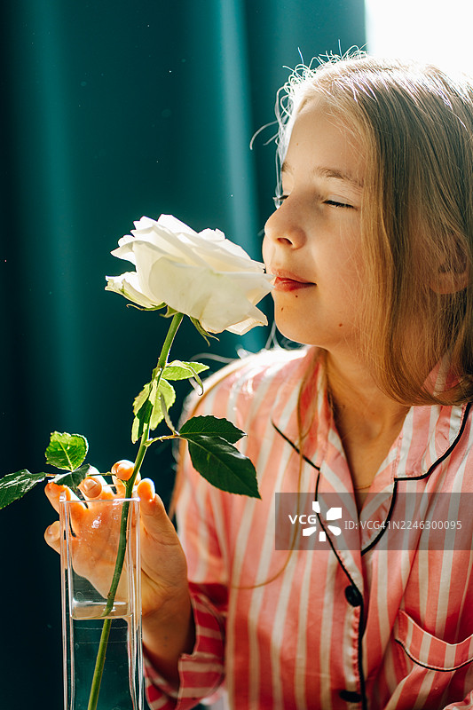 阳光下，女孩闭着眼睛闻着白玫瑰图片素材