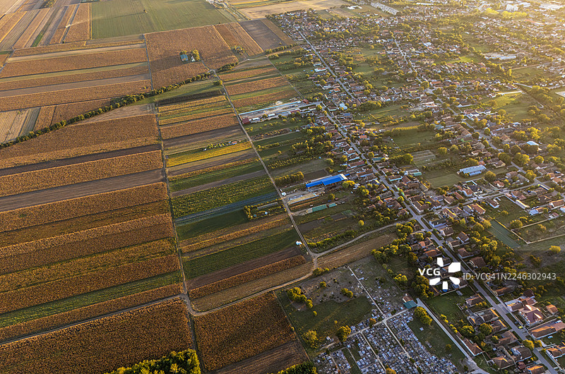 傍晚时分，无人机从高空俯瞰风景如画的小镇，屋顶和街道沐浴在金色的晚霞中。图片素材