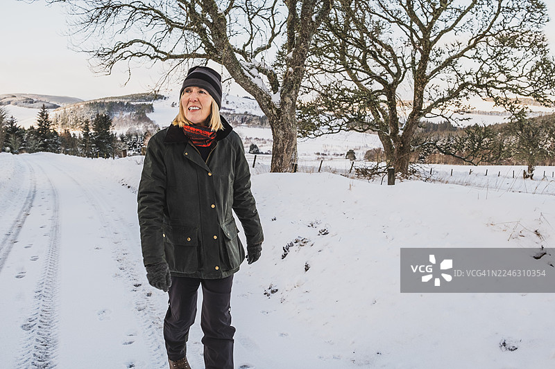 一位年长女性在苏格兰乡村进行冬季散步图片素材