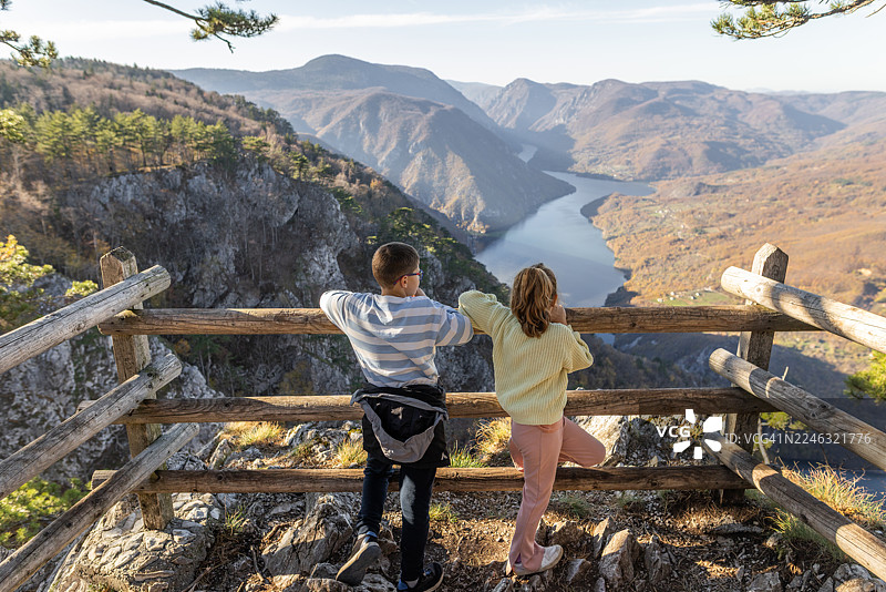 两个孩子从一个质朴的木栅栏观景点俯瞰山谷图片素材