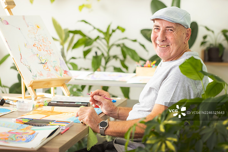 一位资深插画师在种满植物的画室里绘画图片素材