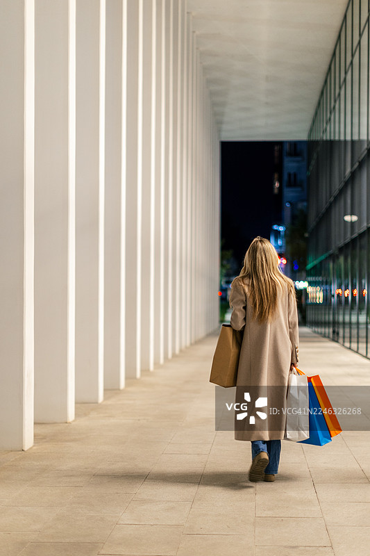 提着购物袋的女士走在现代都市的户外图片素材