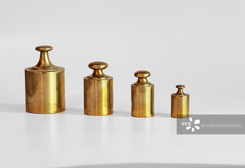 四件不同尺寸和重量的青铜砝码，背景为白色。砝码的历史，本质上是人类对测量精度和普遍性的不懈追求。图片素材