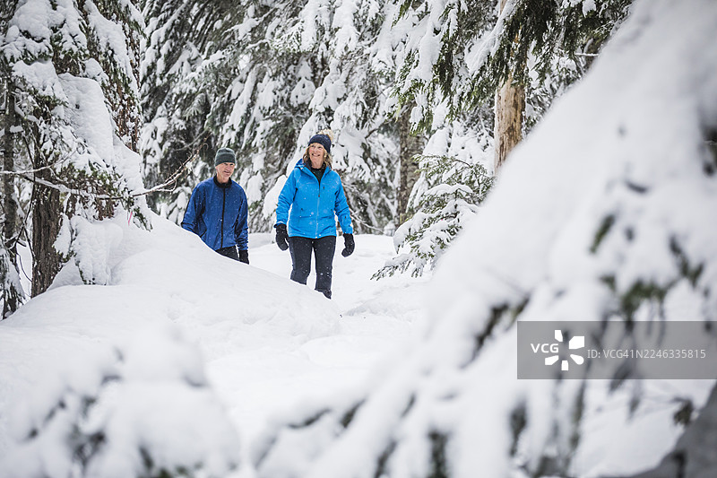 成熟夫妇在惠斯勒的深雪森林中穿雪鞋行走图片素材