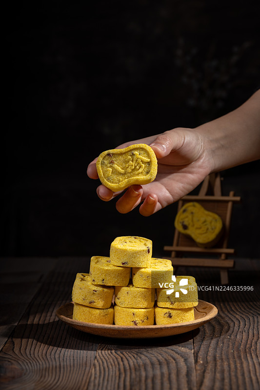 桌上的黄色甜点糕点，一只手拿起其中一个图片素材