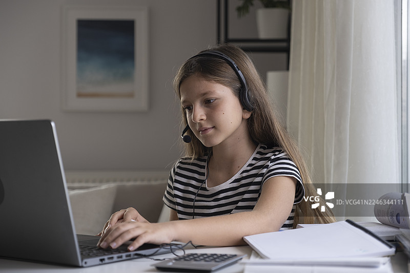 戴着耳机的女孩正在用笔记本电脑在线学习，参与远程教育图片素材