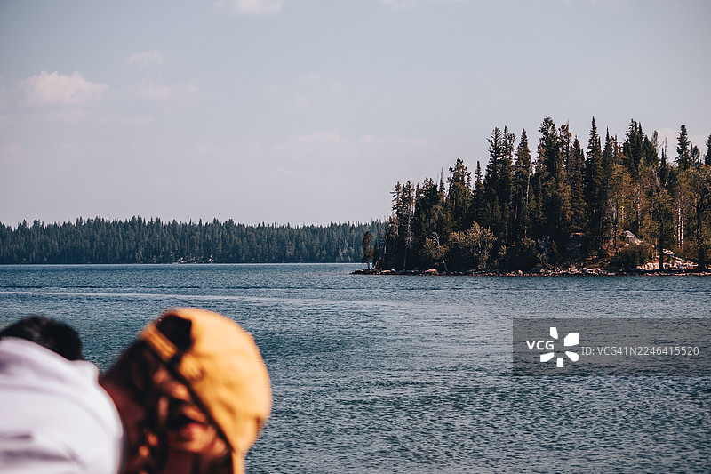 背影：人们在晴朗的天空下，望着地平线上的森林和宁静的湖泊，杰克逊，美国，美国，大提顿国家公园图片素材