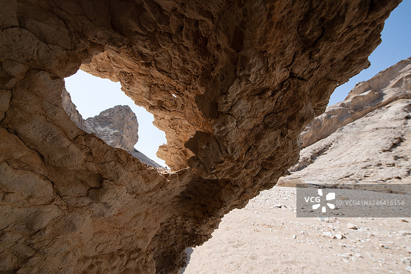 从低角度拍摄的自然岩层，背景是晴朗的天空，位于阿拉伯联合酋长国艾因的哈菲特山沙漠景观中图片素材