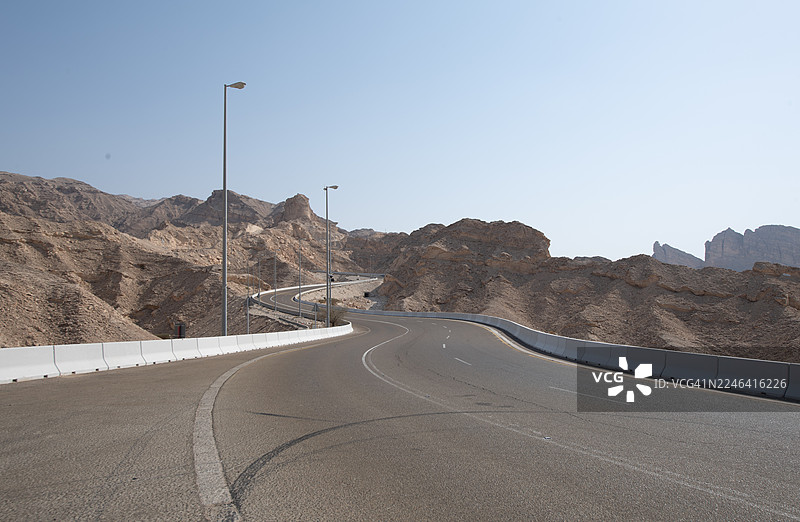 晴朗天气下，蜿蜒的山路穿过干旱的沙漠景观，位于阿联酋艾恩的杰贝尔哈菲特。图片素材