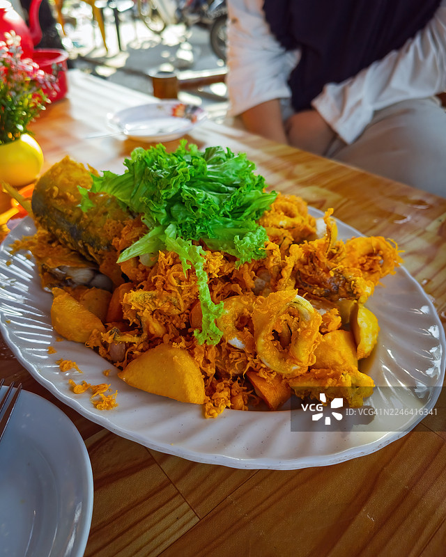餐厅户外，盘子里盛着美味的炸鱼和炸鱿鱼，配上新鲜的生菜图片素材