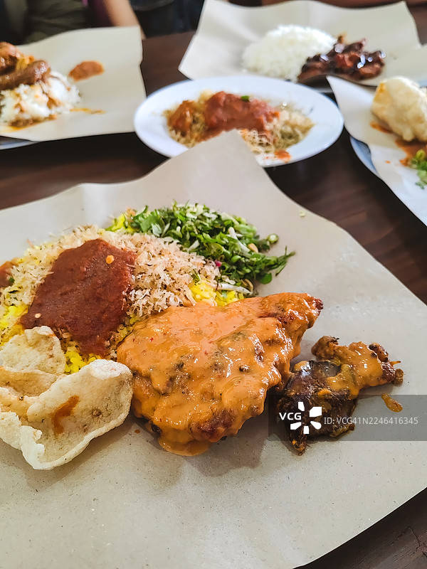 俯视角度拍摄的美味马来西亚椰浆饭（Nasi Kerabu），摆放在餐桌上，旁边还有其他菜肴，正待享用。图片素材