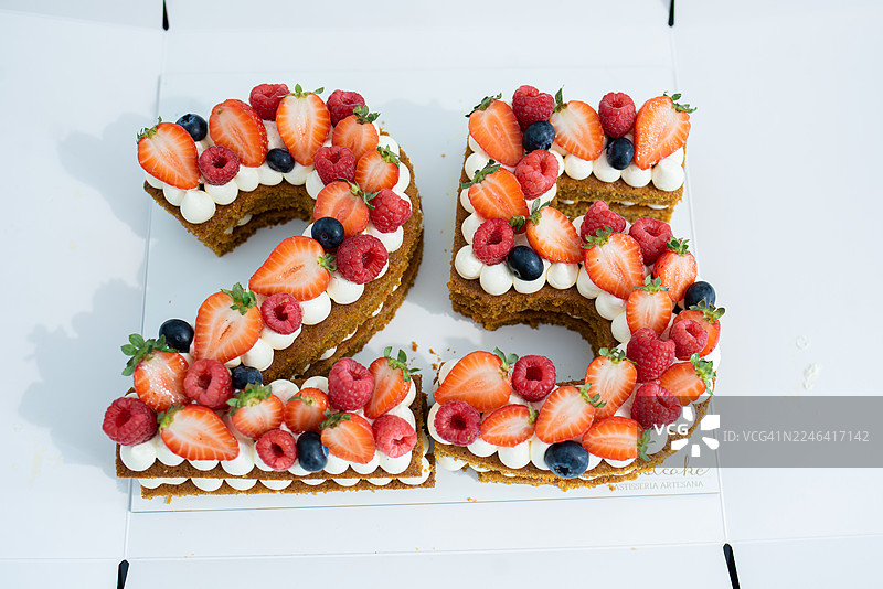 俯视视角下的数字25蛋糕，装饰有新鲜浆果和奶油，非常适合25岁生日或周年纪念庆典图片素材
