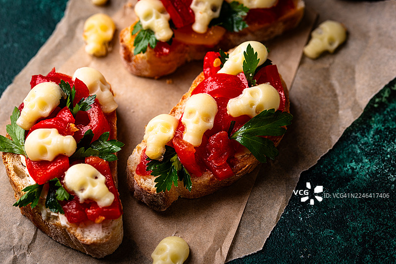万圣节惊悚烤面包片，配有红椒和奶酪骷髅，摆放在乡村风格的桌子上图片素材