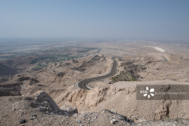 清晰天空下的广阔干旱沙漠景观，蜿蜒的道路，全景航拍视角，阿联酋艾因，哈菲特山图片素材