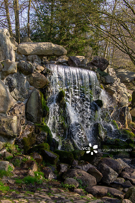 宁静森林中，壮丽的瀑布倾泻而下，越过覆盖着苔藓的岩石，位于荷兰阿纳姆。图片素材
