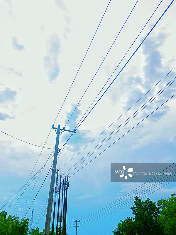 低角度拍摄的电力塔和输电线路，背景是多云的天空，象征着电力、基础设施和现代生活。图片素材