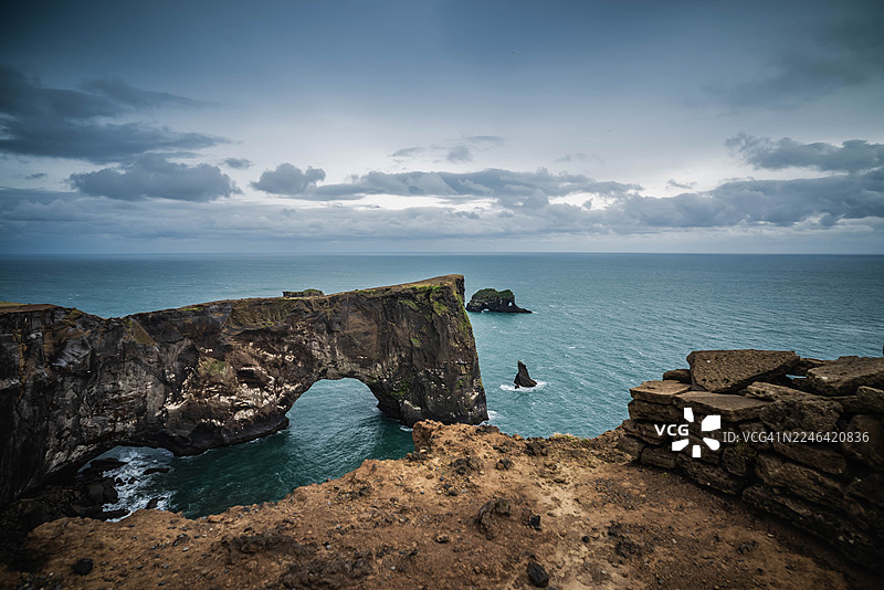 冰岛戏剧性的海岸景观，以天然岩石拱门、汹涌的大海和多云的天空为特色图片素材