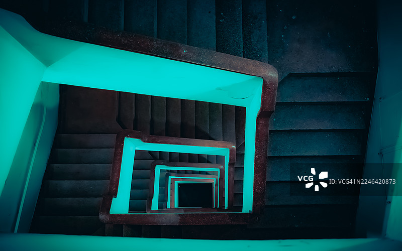 俯视螺旋楼梯，发光的青色扶手向下延伸，营造出抽象而神秘的视觉效果，巴西图片素材