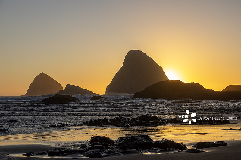 美国提拉穆克县，海边栈桥和拍打在沙滩上的海浪的戏剧性海岸日落剪影图片素材