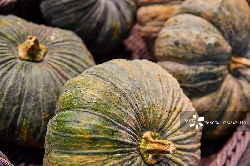 市场摊位上绿橙相间的南瓜特写，已准备好出售图片素材