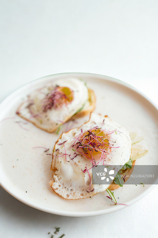 吐司上美味的煎蛋配微型蔬菜，盛放在白盘中图片素材