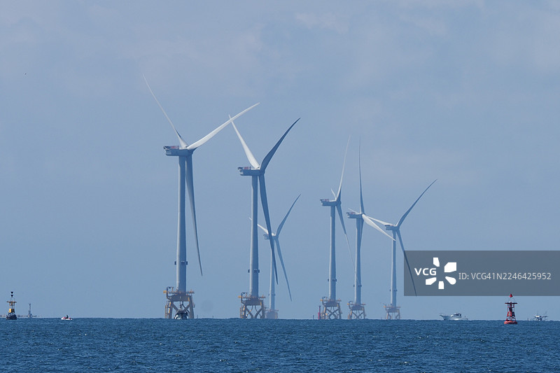 海上风电场，多台风力发电机在海洋上产生清洁能源，背景是朦胧的天空，象征着可再生能源和环境可持续性，日本，JP图片素材