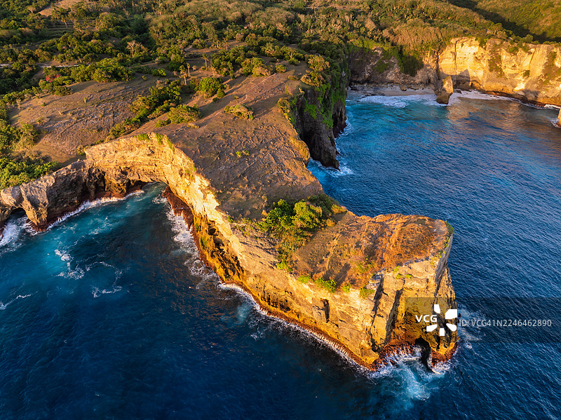 印尼巴厘岛努沙佩尼达岛破碎海滩的航拍图。黄金时刻拍摄的标志性海岸岩石拱门、绿松石般的海水和戏剧性的悬崖，在充满活力的热带风光中从空中捕捉。图片素材