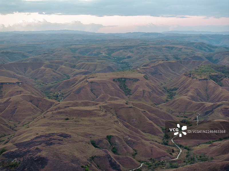 壮观的空中全景展现了印度尼西亚松巴岛独特起伏的山丘和广阔的开放景观，天空动态变化。在日出时分，见证这个偏远而迷人的目的地原始、狂野的美丽。图片素材