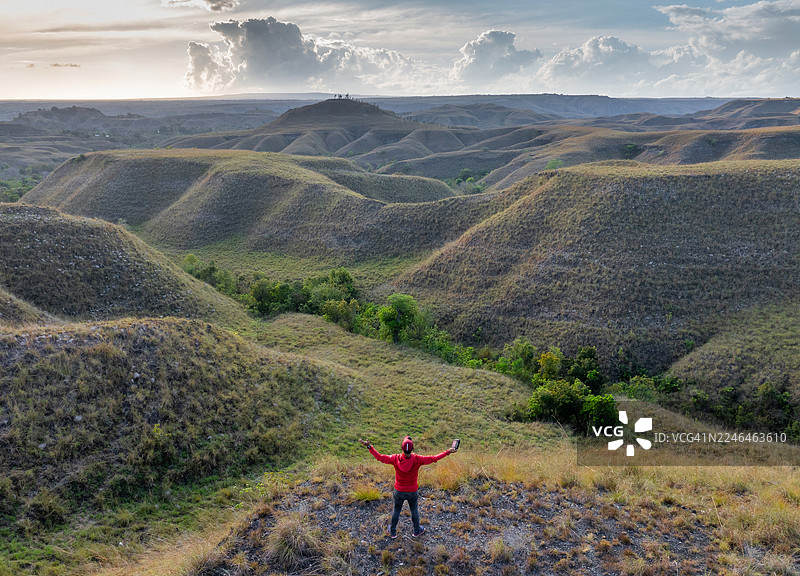 壮观的航拍全景图捕捉了印度尼西亚松巴岛独特起伏的山丘和广阔的开阔景观，天空变幻莫测。在日出时分，见证这个偏远而迷人的目的地原始、未经雕琢的美丽。图片素材