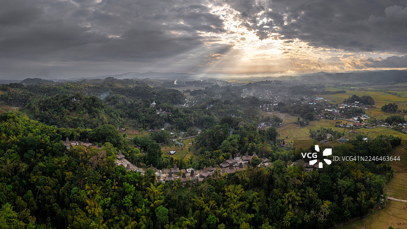 引人入胜的印度尼西亚普拉金村景色，展示了其标志性的传统房屋，坐落在郁郁葱葱的绿色山丘和肥沃的稻田之间。这些图像捕捉了独特的建筑图片素材