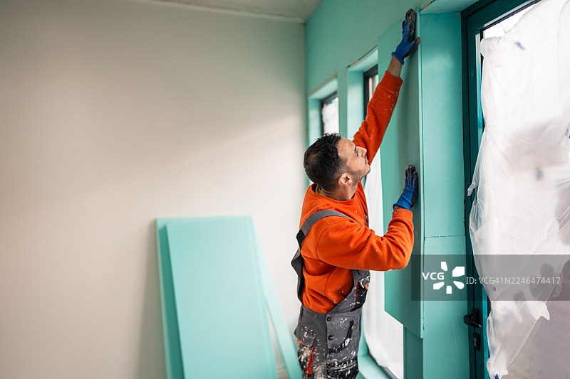 男子在房屋翻新项目期间安装XPS隔热板图片素材