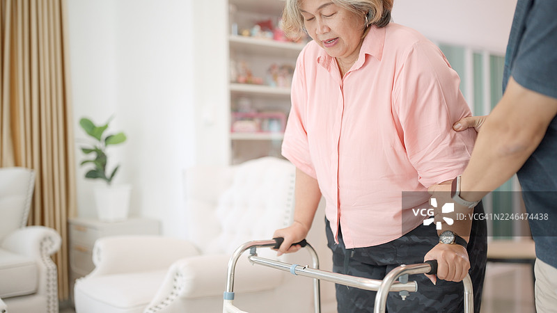 退休夫妇互相照顾健康。退休活动、生活方式、幸福感以及身心健康。老年人康复后进行锻炼。亚洲丈夫照顾正在拄拐杖锻炼的妻子。图片素材