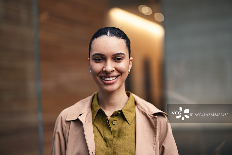 面带微笑的商界女性站在城市街道上，展现出自信和专业图片素材