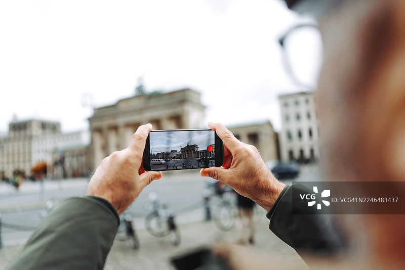 一名男子正用智能手机拍摄勃兰登堡门图片素材