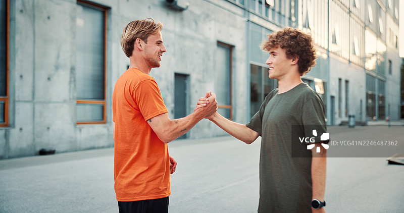 男人，朋友，在城市中握手，健身，快乐，打招呼，尊重，训练日常。人们，伙伴，微笑握手，联系，在城市户外锻炼。图片素材