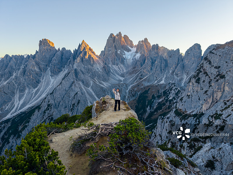 一位女士站在悬崖上，背景是意大利多洛米蒂山脉的卡迪尼迪米苏里纳峰。图片素材