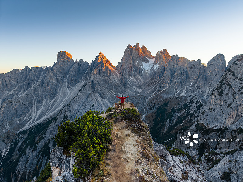一名男子站在悬崖上，背景是意大利多洛米蒂的米苏里纳卡迪尼山峰图片素材