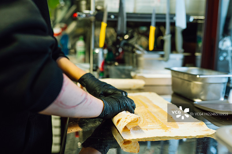 双手在制作街头食品卷饼，淋上酱汁图片素材