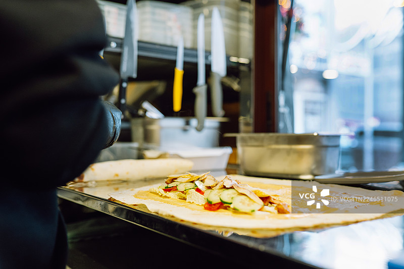 厨师站着，展示着一份带有蔬菜的新鲜街头食品卷饼图片素材