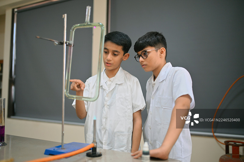 初中男生在学校实验室用U型管和本生灯进行对流实验图片素材