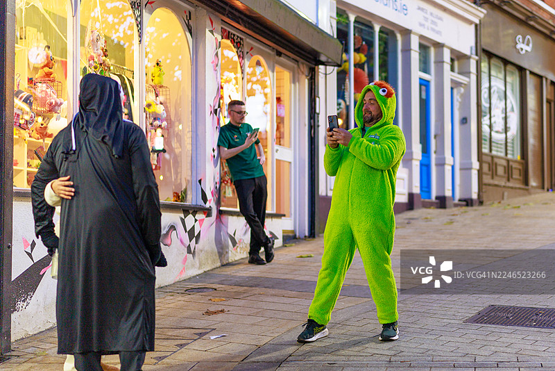 身穿绿色服装的男子正在拍摄万圣节场景图片素材
