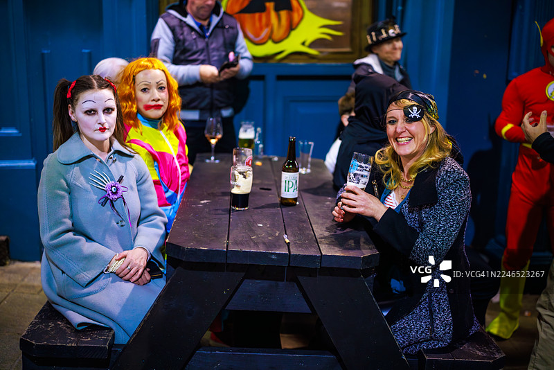 身着多彩服装的女性正在享用万圣节饮品图片素材