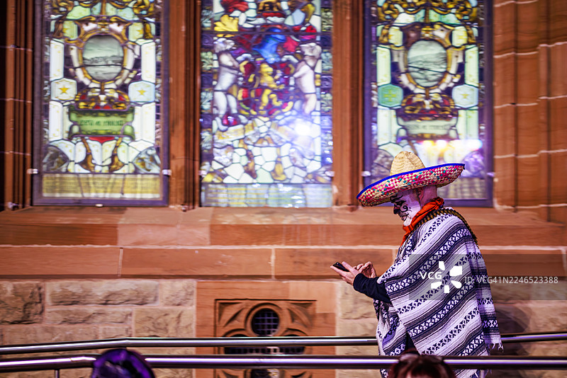 戴着墨西哥帽的万圣节行者在历史悠久的市政厅前图片素材