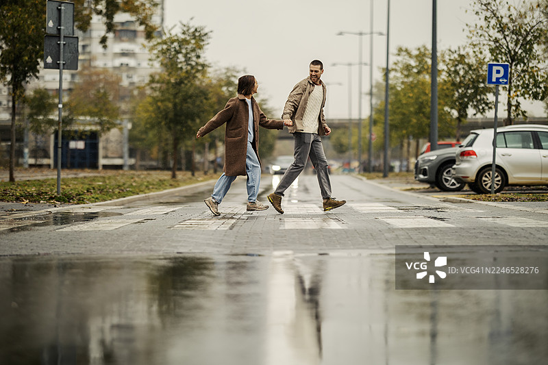 情侣在雨中牵手走过城市街道图片素材