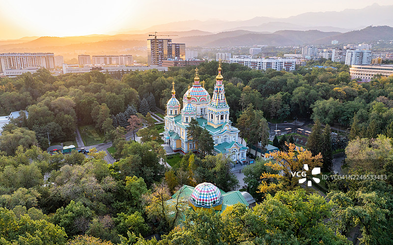 日出时分的阿拉木图圣升天主教座堂和28潘菲洛夫公园的空中视角，背景是沐浴在金色时光温暖光线下的山脉。图片素材