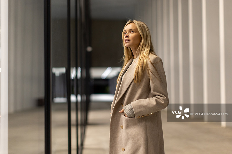 一位女性在现代城市户外橱窗前驻足图片素材