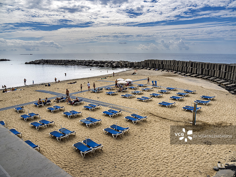 俯瞰马德拉岛海边沙滩，有遮阳伞、躺椅和游泳的人们。图片素材