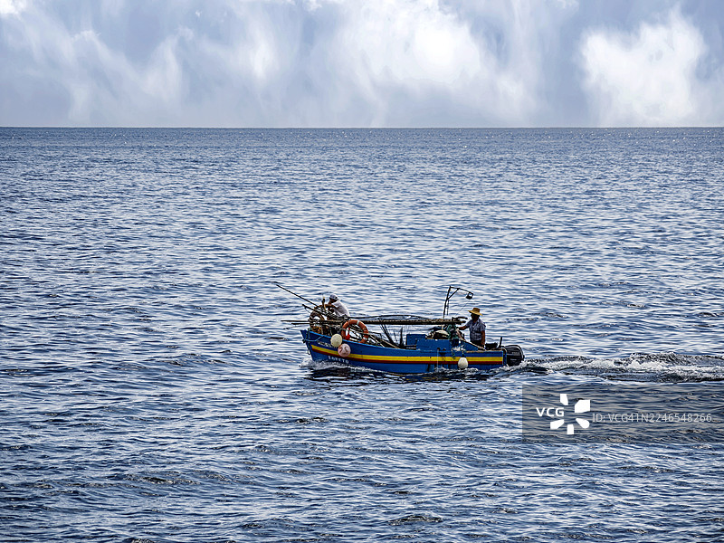 马德拉岛海岸边，渔民们在一艘小型手工渔船上作业。图片素材