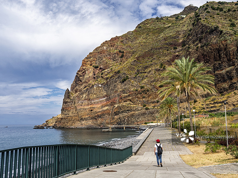 一位女士在马德拉岛的海滨长廊上散步。图片素材