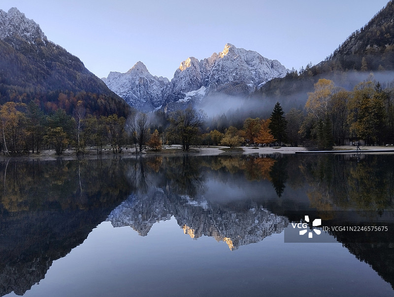 秋季，雄伟的雪山峰倒映在平静的湖水中，斯洛文尼亚图片素材